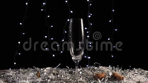 好香槟酒手从桌上的瓶子里倒出一瓶金色的起泡葡萄酒白色的雪花和五彩纸屑与灯光交相辉映视频的预览图