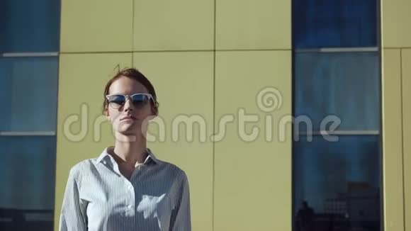 戴太阳镜的年轻女子在商业建筑阳台上摆姿势视频的预览图