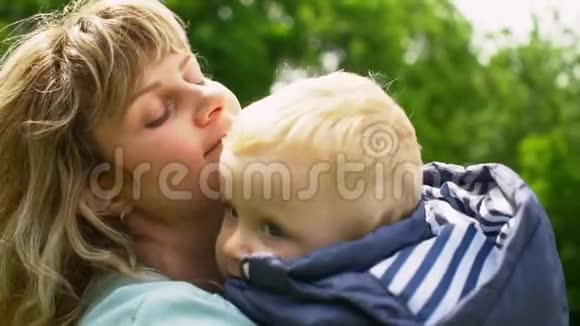 快乐的家庭年轻的妈妈和可爱的孩子在公园里接吻和拥抱视频的预览图