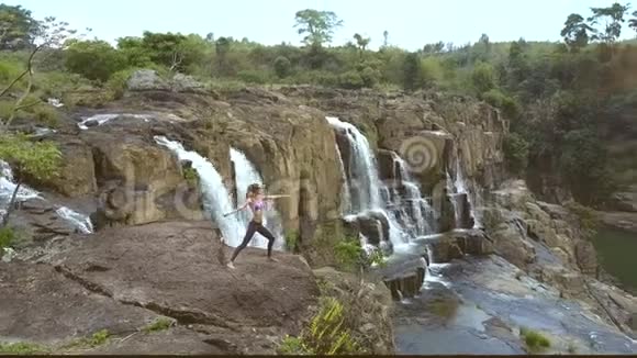上景妇女在石上瑜伽姿势瀑布视频的预览图