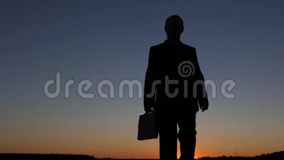 商人的剪影带着公文包在夕阳下对着蓝天视频的预览图