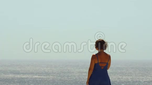 年轻女子穿着蓝色的夏装欣赏风景视频的预览图