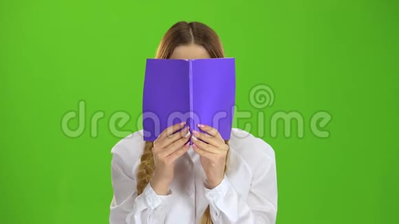 女学生用笔记本遮住了她的脸绿色屏幕视频的预览图