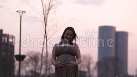 紧紧抱着肚子年轻的孕妇在她的旅行目的地国家拉脱维亚可以俯瞰城市视频的预览图