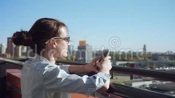 年轻商务女性在阳台上发短信视频的预览图