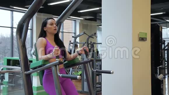 一位深色头发的女运动员的肖像她正在健身房锻炼她的腹肌做腿部的训练视频的预览图