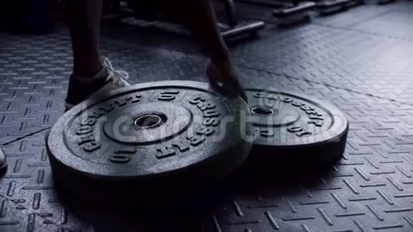 关闭健身房地板上的重物板准备供男子用于力量锻炼男子健身视频的预览图