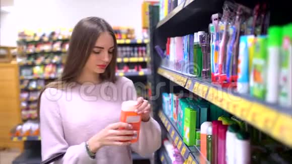 一个购物狂研究身体护理产品和享受步行之间的商店货架可爱的女性20多岁视频的预览图