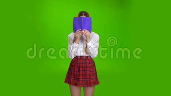 女学生用紫色的笔记本遮住了她的脸绿色屏幕视频的预览图