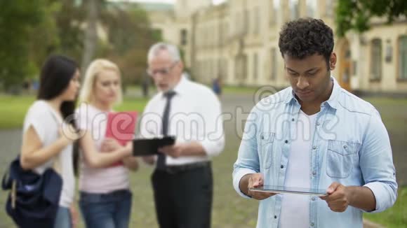 西班牙裔男子站在大学附近在平板电脑上做作业教育应用程序视频的预览图