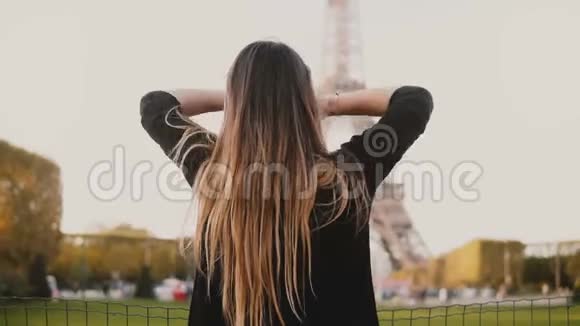 年轻快乐的女人站在法国巴黎埃菲尔铁塔附近然后回头看着相机微笑着视频的预览图
