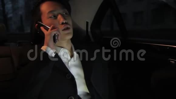 韩国商人的肖像他在智能手机上用黑色舒适的出租车交谈视频的预览图