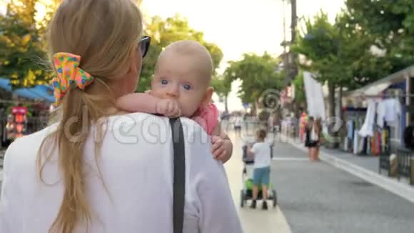 年轻的母亲带着小女儿在城市大街上散步视频的预览图