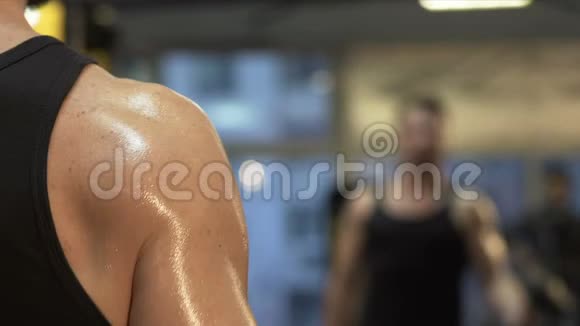 肌肉男在镜子前举起大哑铃在健身房积极锻炼视频的预览图