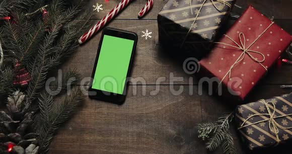 上景黑色智能手机与绿色屏幕躺在桌子上与圣诞节假日装饰圣诞老人的手视频的预览图