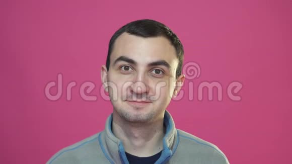 粉红色背景下一个年轻英俊的快乐男人的肖像视频的预览图