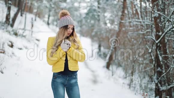 戴着冬帽的漂亮女人温暖了她的双手站在雪上的双手视频的预览图