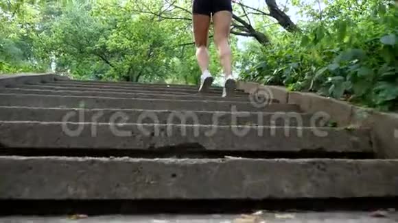 美丽的运动型金发女郎穿着T恤和短裤夏天跑上楼在森林里公园里视频的预览图