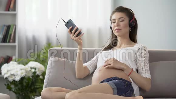 期待女士在手机上听轻松的音乐揉揉肚子视频的预览图