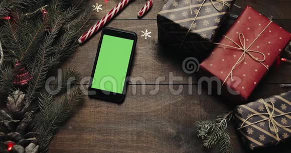 上景黑色智能手机与绿色屏幕躺在桌子上与圣诞节假日装饰圣诞老人的手视频的预览图