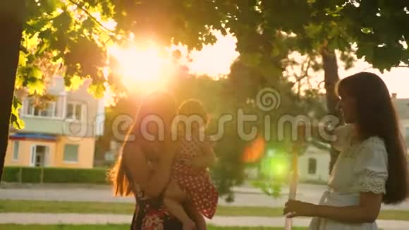 妈妈和她的女儿在城市公园里捕捉到大而透明的肥皂泡在耀眼的阳光下大笑视频的预览图
