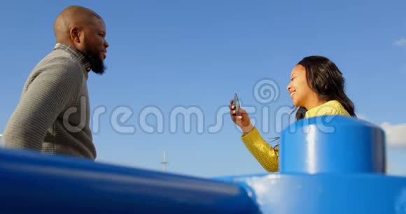 阳光明媚的4k一对情侣在公园里用手机拍照视频的预览图