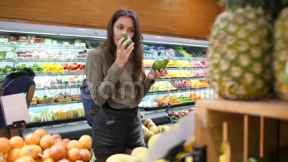 年轻女性在杂货店选择鳄梨纯素零废物女孩购买水果和素食在有机超市4K视频的预览图