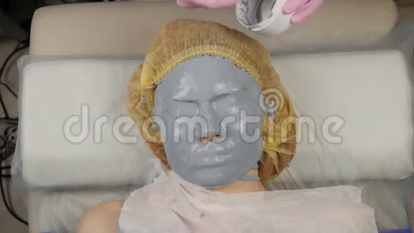美容师在水疗沙龙为女性脸涂抹泥面膜面部年轻化程序水疗视频的预览图