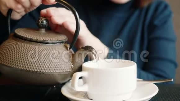 女孩把茶倒进一个杯子里一个女人从茶壶里洒茶视频的预览图