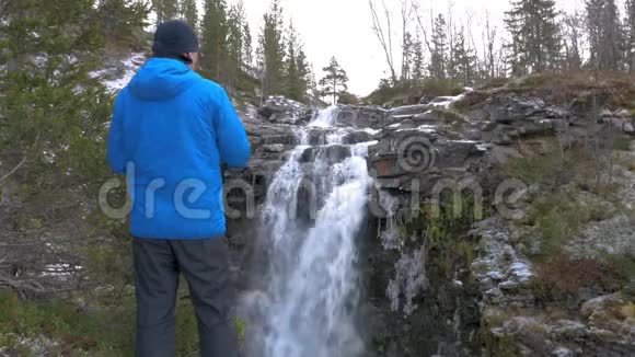 一个穿着运动服的人在瀑布附近休息3他在山上拍了一幅美丽的风景画视频的预览图