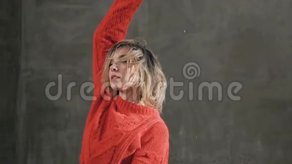 美丽的舞蹈家女孩穿着红色的毛衣和黑色的短裤在工作室里的水滴下跳舞视频的预览图