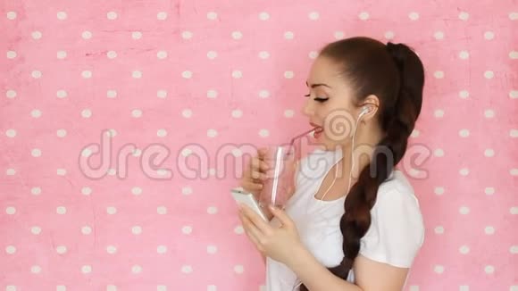智能手机健身妇女喝浆果冰果汁使用智能手机应用程序粉色背景视频的预览图