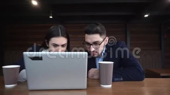 年轻女孩和年轻人坐在咖啡馆里手提电脑和讨论项目视频的预览图