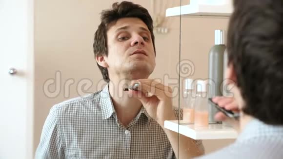 人在照镜子时刮胡子穿着格子浅色衬衫的布鲁内特视频的预览图