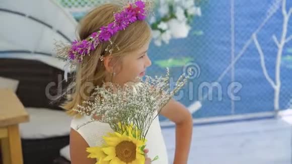 一个金发碧眼的小女孩戴着的皇冠手里拿着花在沙滩上旋转视频的预览图