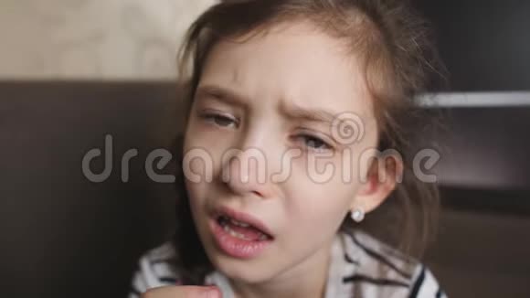 一个可爱的小女孩摇摇晃晃地摇晃着她松动的牙齿想把它拔掉视频的预览图
