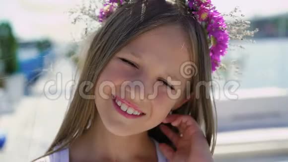 在海湾酒吧的镜头前戴着鲜花皇冠的可爱女孩的肖像4K视频的预览图