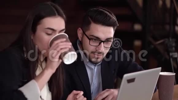 两个同事在咖啡时间用笔记本电脑讨论案件视频的预览图