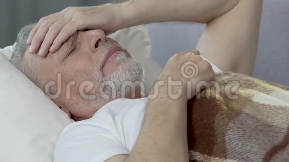 老人躺在床上不眠不休用手抵着额头头痛得厉害视频的预览图