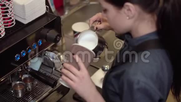 女咖啡师准备将牛奶倒入纸杯中加入咖啡并在牛奶上画在牛奶上视频的预览图