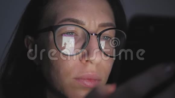 一位戴眼镜的女士坐在沙发上用智能手机进行网上购物网上营销视频的预览图