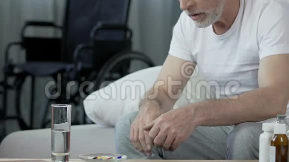 老年男性吃药看着轮椅站在后台外伤视频的预览图