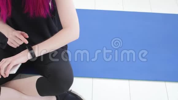 体育健身理念年轻女运动员坐着使用健身追踪器和智能手机视频的预览图