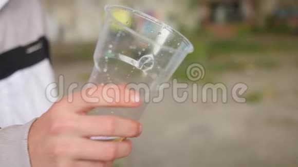 把柠檬水从杯子里倒入塑料玻璃里近距离射击视频的预览图