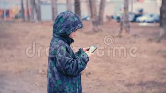 男孩拨一个号码在公园里用手机说话视频的预览图