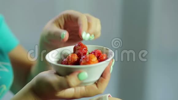 一个女人正在从白色盘子里摘草莓吃视频的预览图