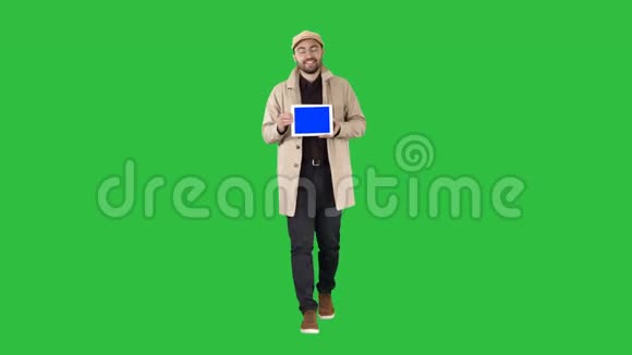 年轻人走着说话在绿色屏幕上显示带有蓝色屏幕模型的数字平板电脑色度键视频的预览图