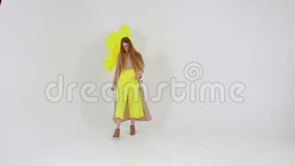 穿着黄色裙子手里拿着黄色气球的女孩正在灯光背景下对着相机摆姿势视频的预览图