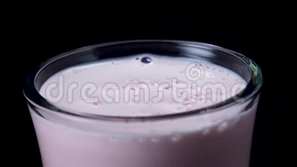 加草莓奶昔的杯子框架在鲜红色的奶昔里把鲜红色的草莓放在黑色上视频的预览图