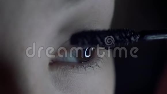 年轻女性在睫毛上涂睫毛膏的宏观镜头中的眼睛视频的预览图